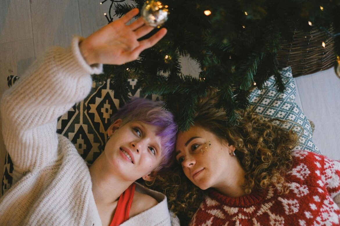 Two beautiful girls are lying on the floor under the Christmas tree